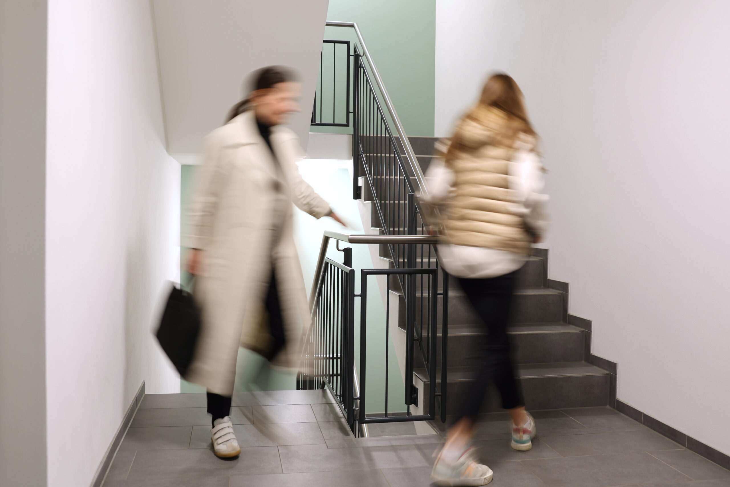 Zwei Frauen die eine Treppe in einem Gebäude nach oben laufen